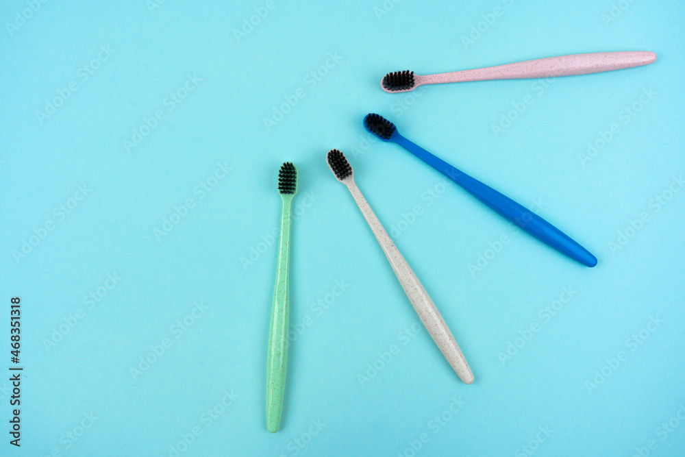 Colored toothbrushes made from recycled plastic on a light blue background with copy space. Top view