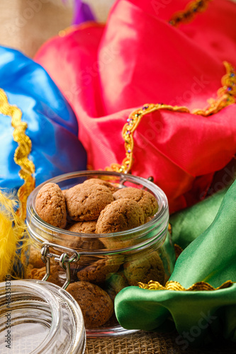 Dutch holiday Sinterklaas traditional cookies kruidnoten in glass jar with colorful piet's hats. Pepernoten, traditional sweets, strooigoed. Concept of Saint Nicholas day. photo