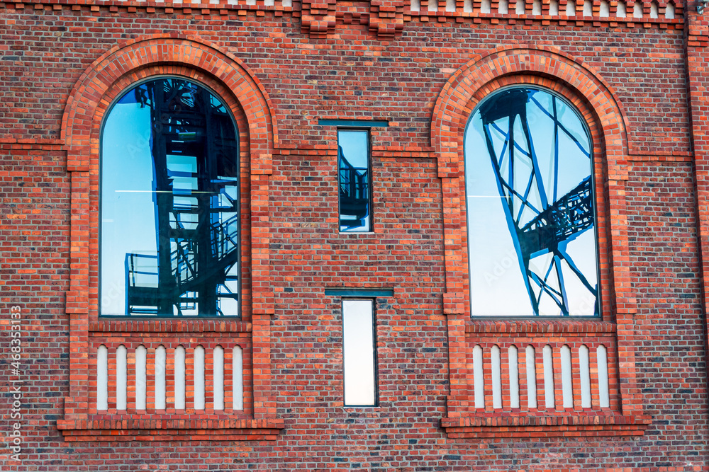 Glossy windows in the engine room building in former coal mine in Katowice, Silesia, Poland - present Silesian Museum. Reflection of the mine shaft tower.