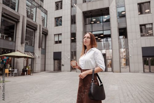  Young business woman holding coffee of the modern office building background 