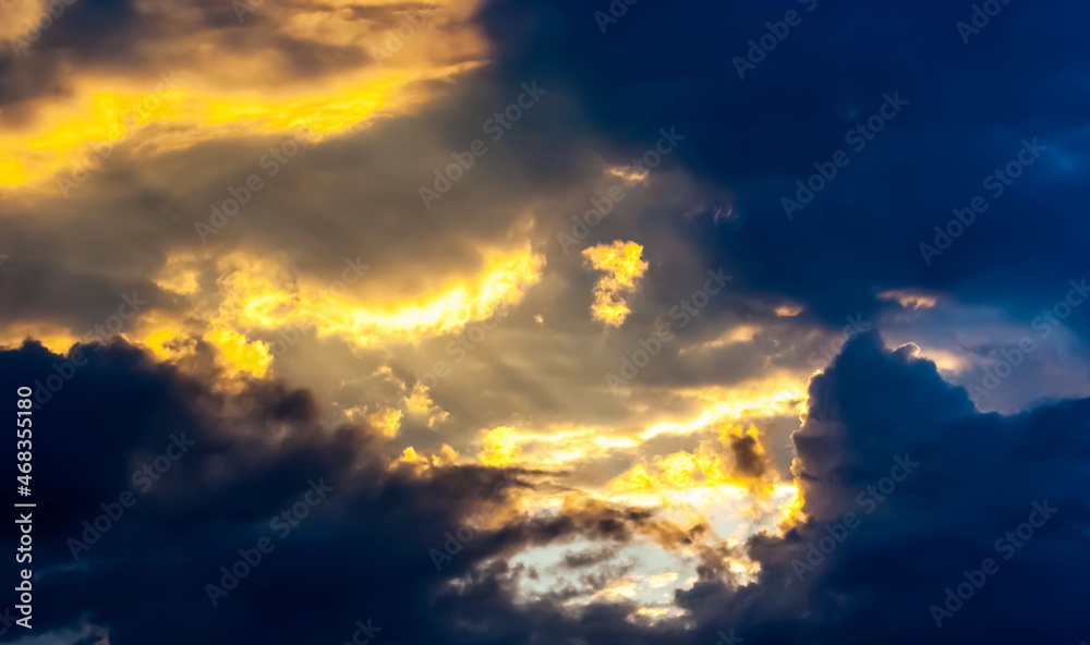 Pre-storm sky with cumulus clouds illuminated by the rays of the setting sun in summer
