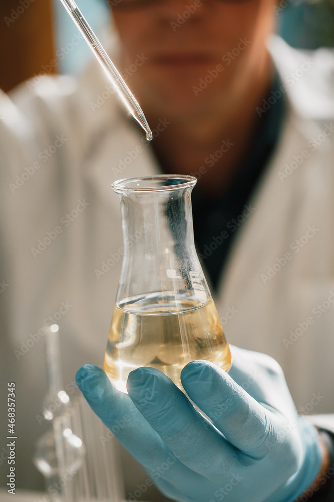 CBD hemp oil, Scientist holding bottle of Cannabis oil against Marijuana plant. Herbal Treatment, Alternative Medicine CBD hemp oil, Scientist holding bottle of Cannabis oil against Marijuana plant. Herbal Treatment, Alternative Medicine