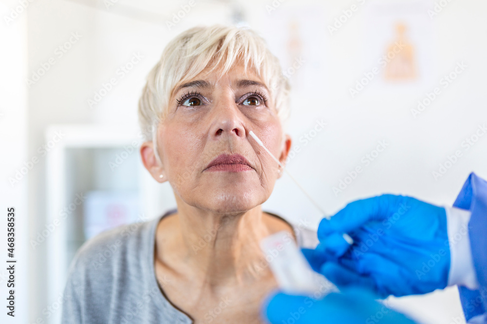 Professional medical worker wearing personal protective equipment testing senior woman for
