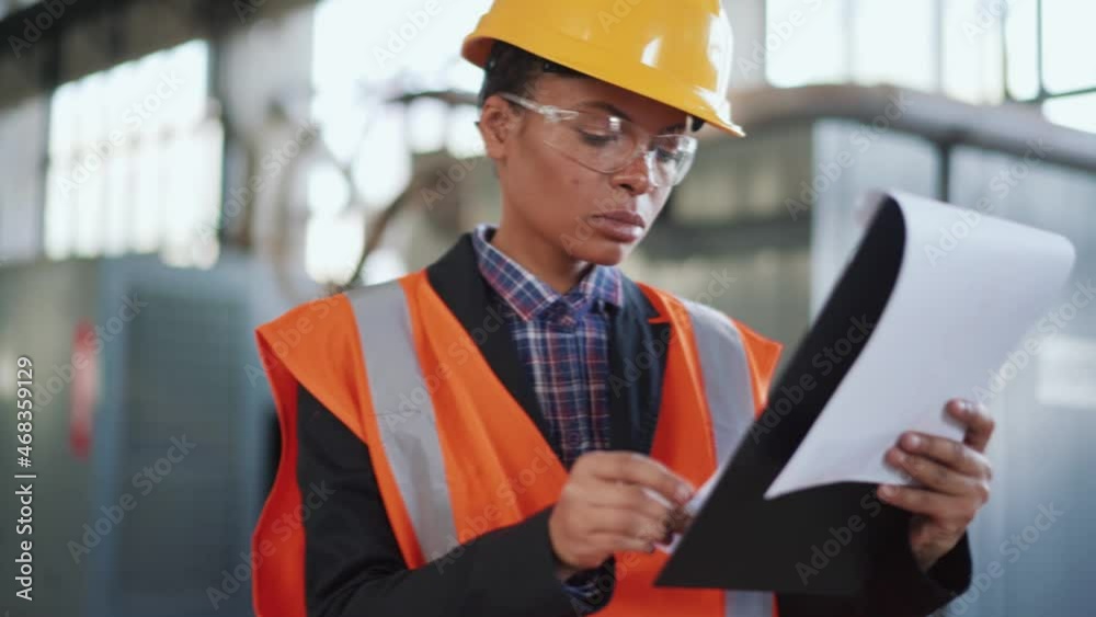 Serious woman engineer in uniform checking papers Serious woman engineer in uniform checking papers