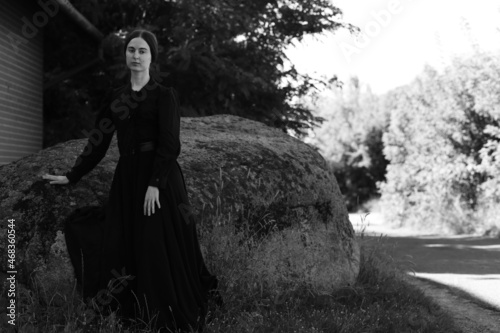 Woman in classic dress near big stone in black and white