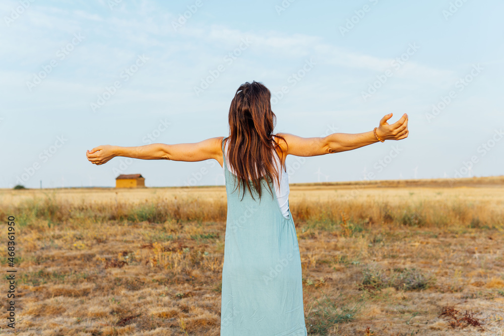 Obraz premium beautiful middle aged young woman with open arms in cereal field breathing fresh air