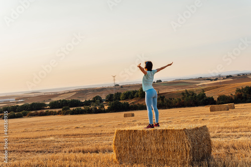 beautiful middle aged young woman with open arms in cereal field breathing fresh air