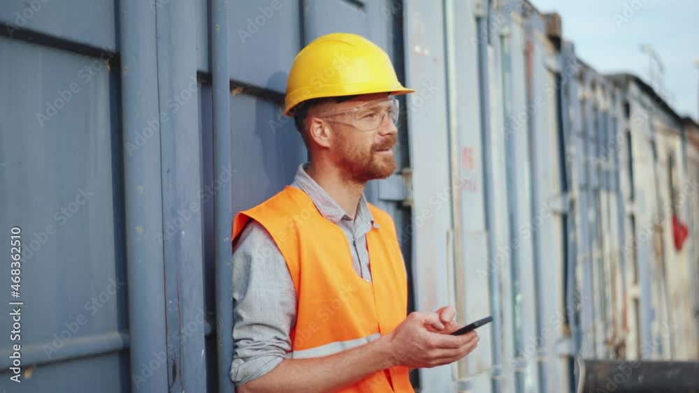 Smiling man shipbuilder in uniform texting by phone Smiling man shipbuilder in uniform texting by phone
