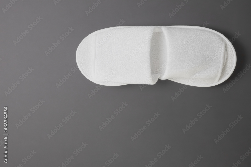 White terry slippers on a gray matte background for home and hotels. Place for text White terry slippers on a gray matte background for home and hotels. Place for text