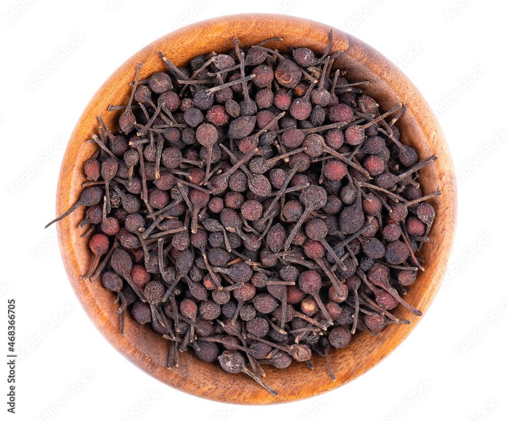 Bourbon pepper in wooden bowl, isolated on white background. Voatsiperifery or bourbonese piper. Madagascar pepper. Top view. Bourbon pepper in wooden bowl, isolated on white background. Voatsiperifery or bourbonese piper. Madagascar pepper. Top view.