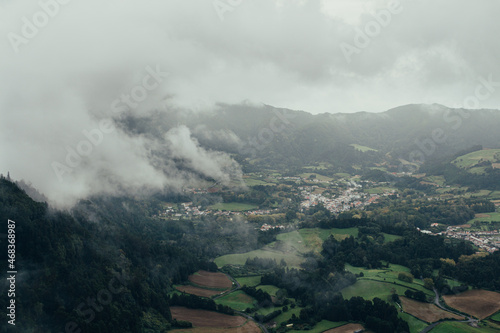 Aerial view of a village between mountains with forests on a foggy day