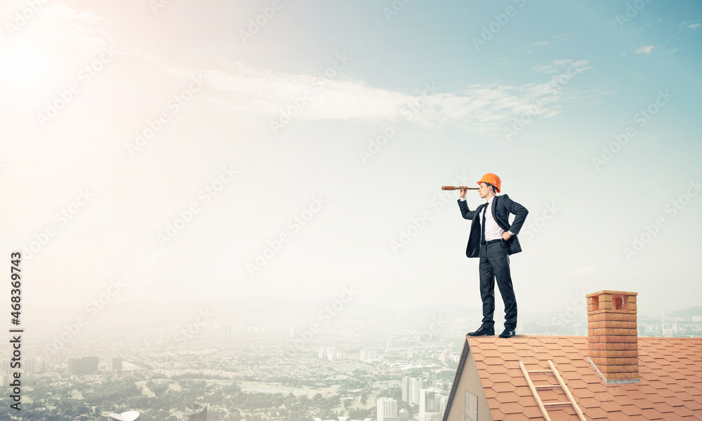 Engineer man standing on roof and looking in spyglass. Mixed med Engineer man standing on roof and looking in spyglass. Mixed med