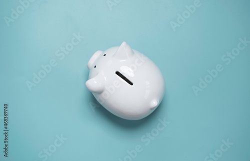 Top view or flat lay of white piggy bank saving on blue background and copy space for deposit and money saving investment concept.