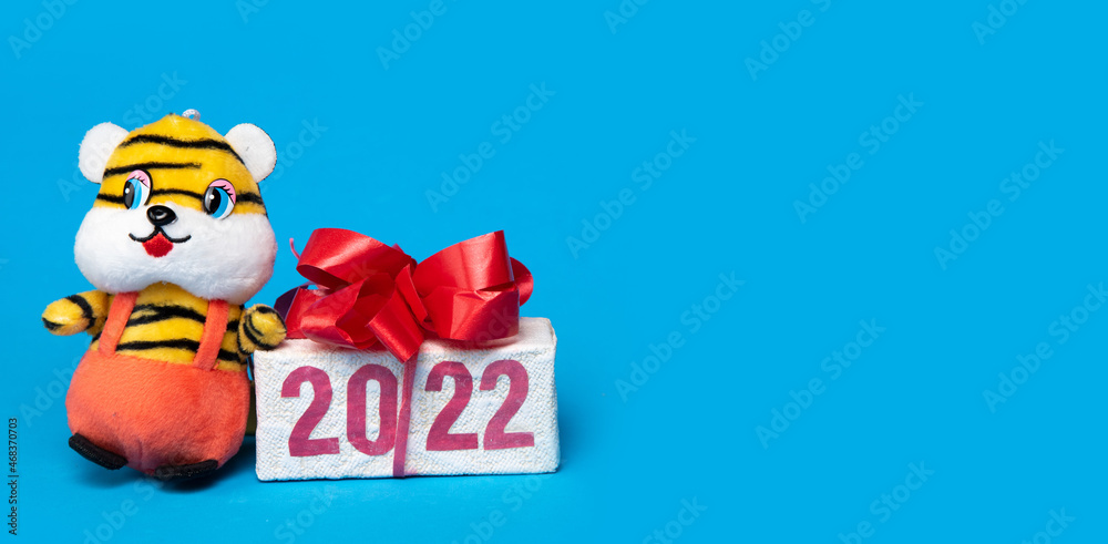 Christmas tiger symbol of 2022 year and gift box with number 2022, new year zodiac sign on blue background.