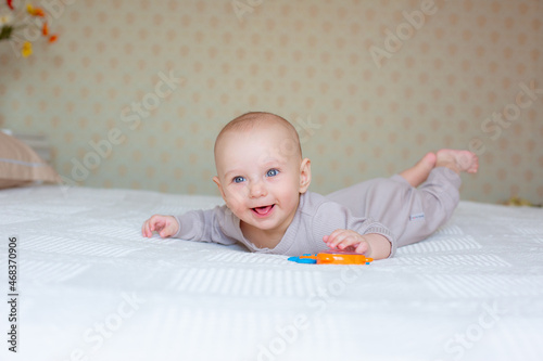 baby boy with a rattle on the bed