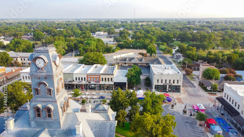 Aerial view close-up Clock Tower of Hood County Courthouse and lush green neighborhood in Granbury, Texas, USA