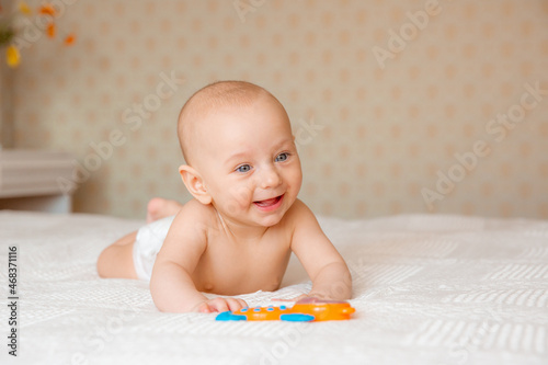 Funny baby in a diaper is playing in the nursery bedroom. A child after a bath or shower on a fresh towel. Changing baby diapers and skin care.