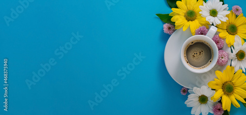 white coffee cup with espresso, flowers on a blue background with free space for text
