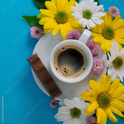 white coffee cup with espresso, flowers on a blue background with free space for text
