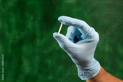 hand in rubber gloves holding a hormonal implant.