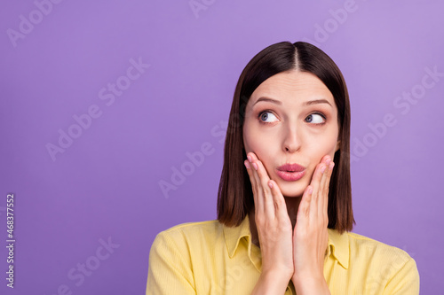 Photo of youth pretty girl arms touch cheeks wondered look empty space isolated over violet color background