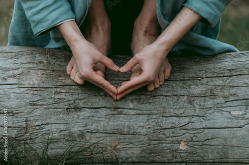 Barefoot person on a tree trunk with hands in heart shape