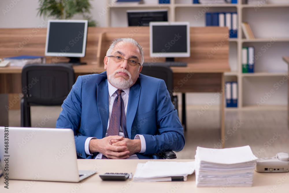 Old businessman employee in wheel-chair working in the office