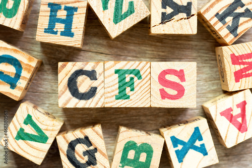 Alphabet letter block in word CFS (Abbreviation of Container Freight Station, Certified fund specialist or Chronic fatigue syndrome) with another on wood background photo