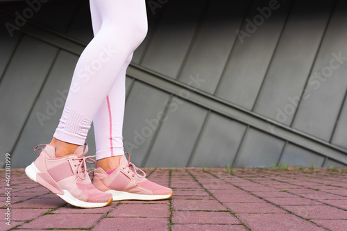 Legs of sportswoman in pink sneakers.