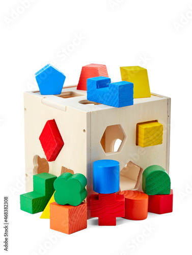 Wooden children's toy that develops a child's fine motor skills, consisting of three-dimensional geometric shapes and holes in a cube for them, isolated on a white background with a shadow.