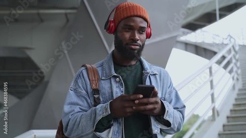 Wallpaper Mural Enjoying music at walk. Concentrated African-American guy in stylish clothes with spbas earphones reads message near footbridge stairs handrails Torontodigital.ca