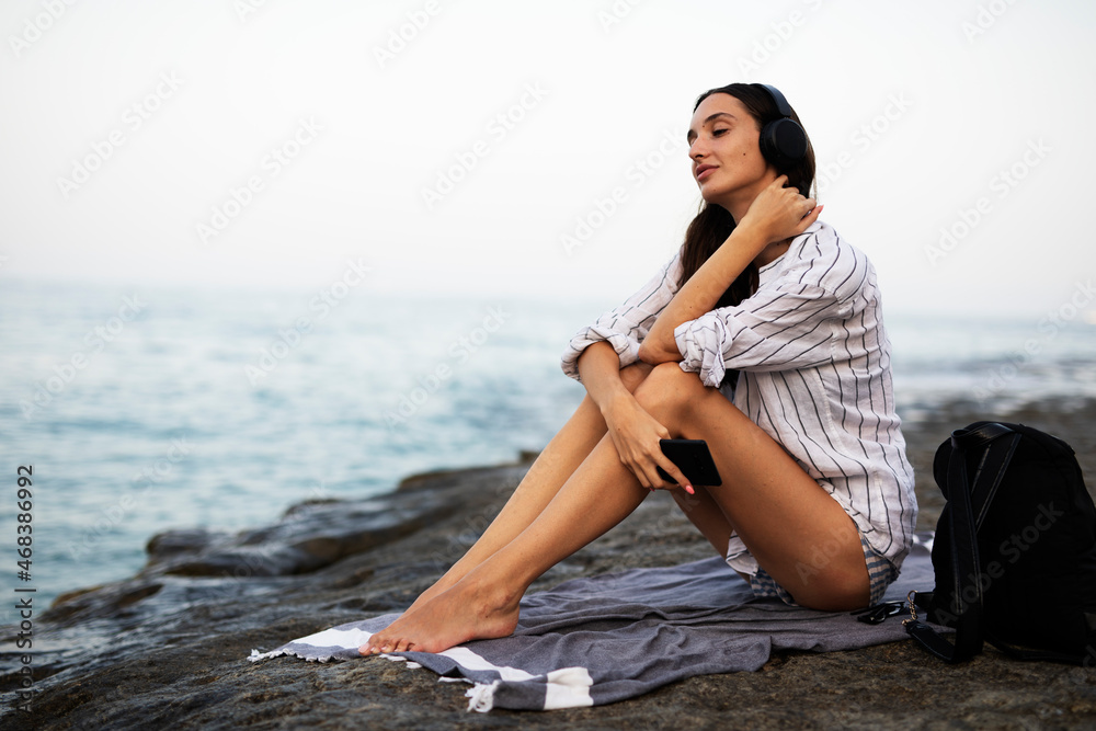 Hot woman relaxing on the sandy beach. Beautiful woman with headphones listening the music Hot woman relaxing on the sandy beach. Beautiful woman with headphones listening the music