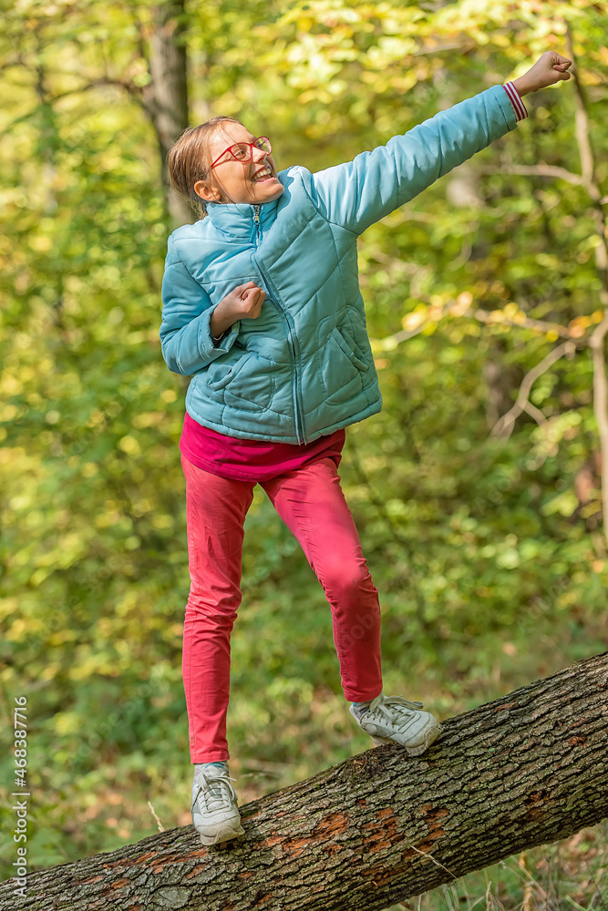 Young Girl standing on Fallen Down Tree Trunk and Catching Balance