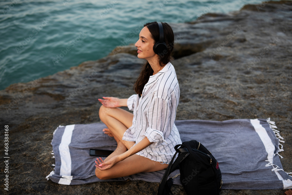Hot woman relaxing on the sandy beach. Beautiful woman with headphones listening the music Hot woman relaxing on the sandy beach. Beautiful woman with headphones listening the music