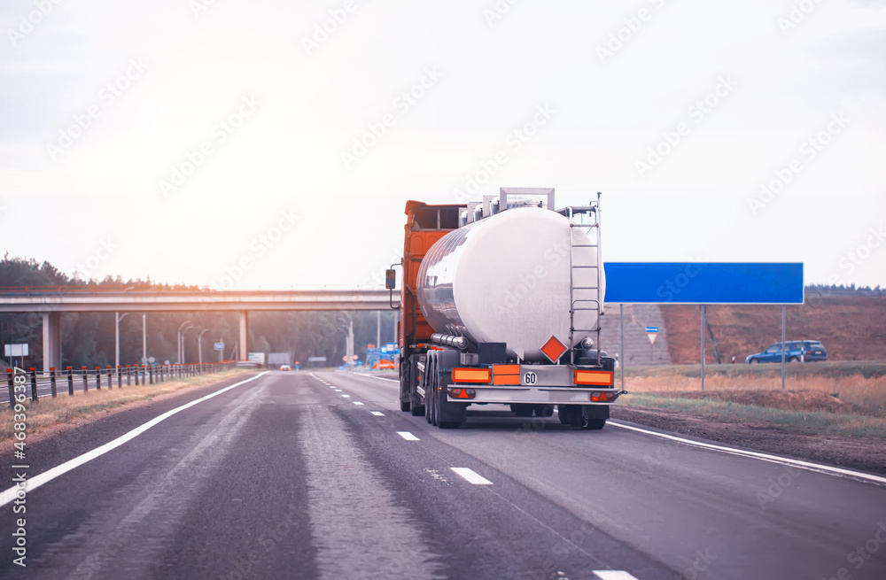 truck with semi-trailer tanker transports dangerous goods on the highway on the background of sunset, industry. Copy space for text