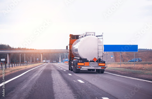 truck with semi-trailer tanker transports dangerous goods on the highway on the background of sunset, industry. Copy space for text