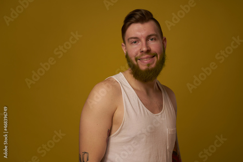 bearded man in white t-shirt with tattoos on his arms posing serious look