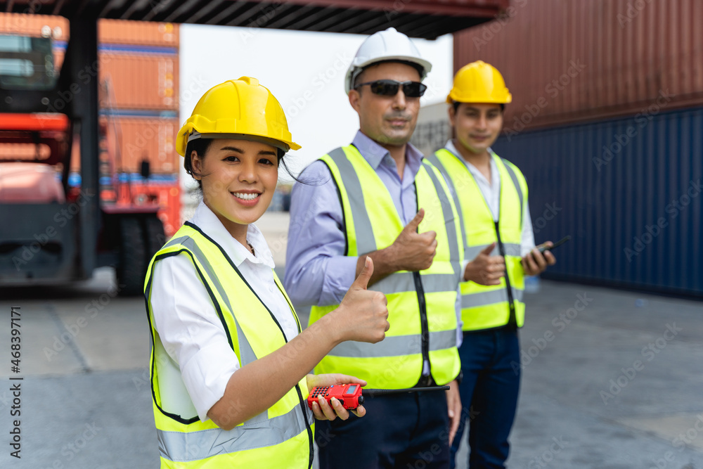 woman worker working with Foreman, standing with ware a yellow helmet to control loading and check a quality of containers from Cargo freight ship for import and export at shipyard or harbor woman worker working with Foreman, standing with ware a yellow helmet to control loading and check a quality of containers from Cargo freight ship for import and export at shipyard or harbor