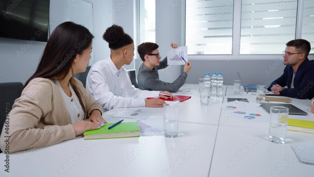 Multiethnic people having meeting in office. Pan shot one of managers reporting on progress and showing growth graph printed on paper. Concept of business Multiethnic people having meeting in office. Pan shot one of managers reporting on progress and showing growth graph printed on paper. Concept of business