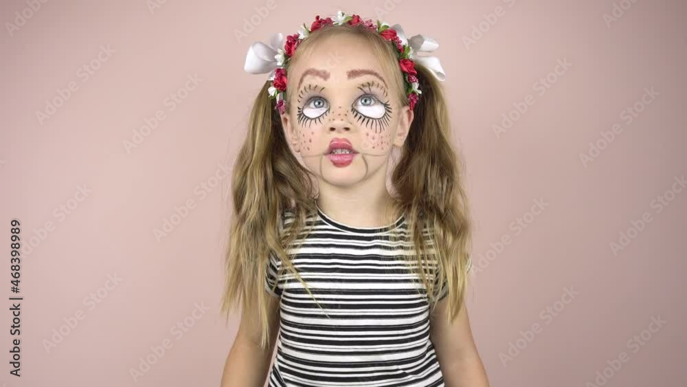 A little girl with make-up on her face depicts puppet grimaces. Mime girl. Close-up A little girl with make-up on her face depicts puppet grimaces. Mime girl. Close-up