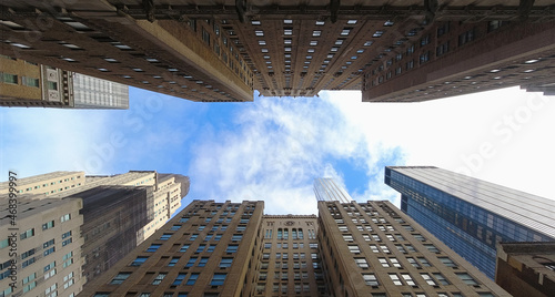 Wide angle panorama of blue sky with clouds between two rows of New York City Midtown buildings 