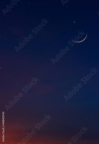 Crescent moon on dark blue twilight sky vertical symbol of Islamic religion and well editing text Arabic Ramadan, Eid al Adha, Eid al Fitr, Muharram on free space