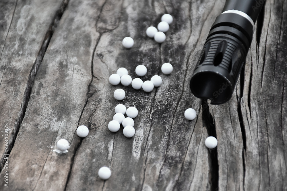 Closeup of white plastic bullets of airsoft gun or bb gun on wooden floor, soft and selective focus on white bullets. - obrazy, fototapety, plakaty 