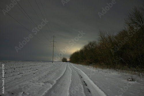 road in winter forest in the night . Night landscape. Nightsky and clouds . Stars in the sky . Lights of the city . Evening forest . Landscapes of Ukraine . Night and morning time 