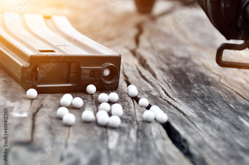 Closeup of white plastic pellets of airsoft gun or bb gun on wooden floor, soft and selective focus on white bullets. photo