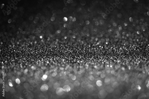 Black glitter lights. Shiny sparkles, bokeh effects, glowing surface. Selective focus, christmas abstract background