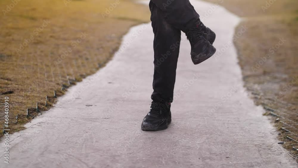 Feet in black pants and boots walking on the ground Feet in black pants and boots walking on the ground