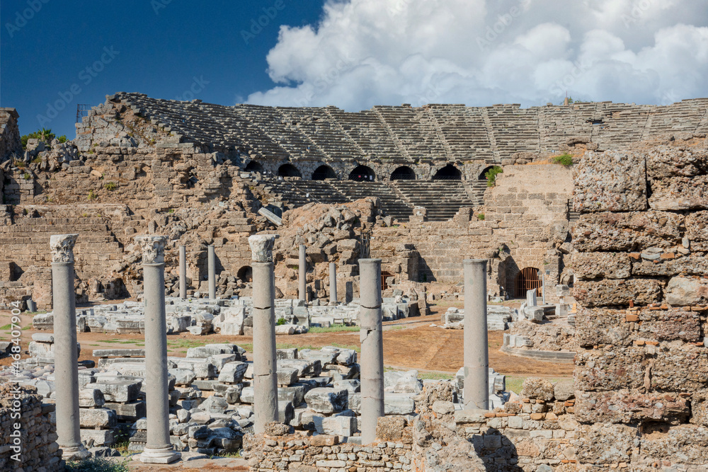 Outside view of Side ancient theater, agora and colonnaded square. Cloudy blue sky. Selective Focus columns and ruins.