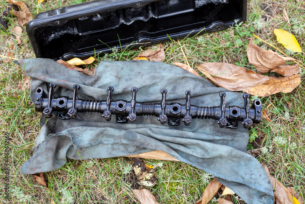 Engine part rocker shaft with rocker arms for valves lies on dirty rag ...