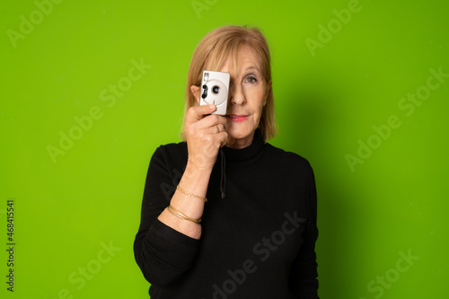 senior female amateur photographer taking photos isolated on green background